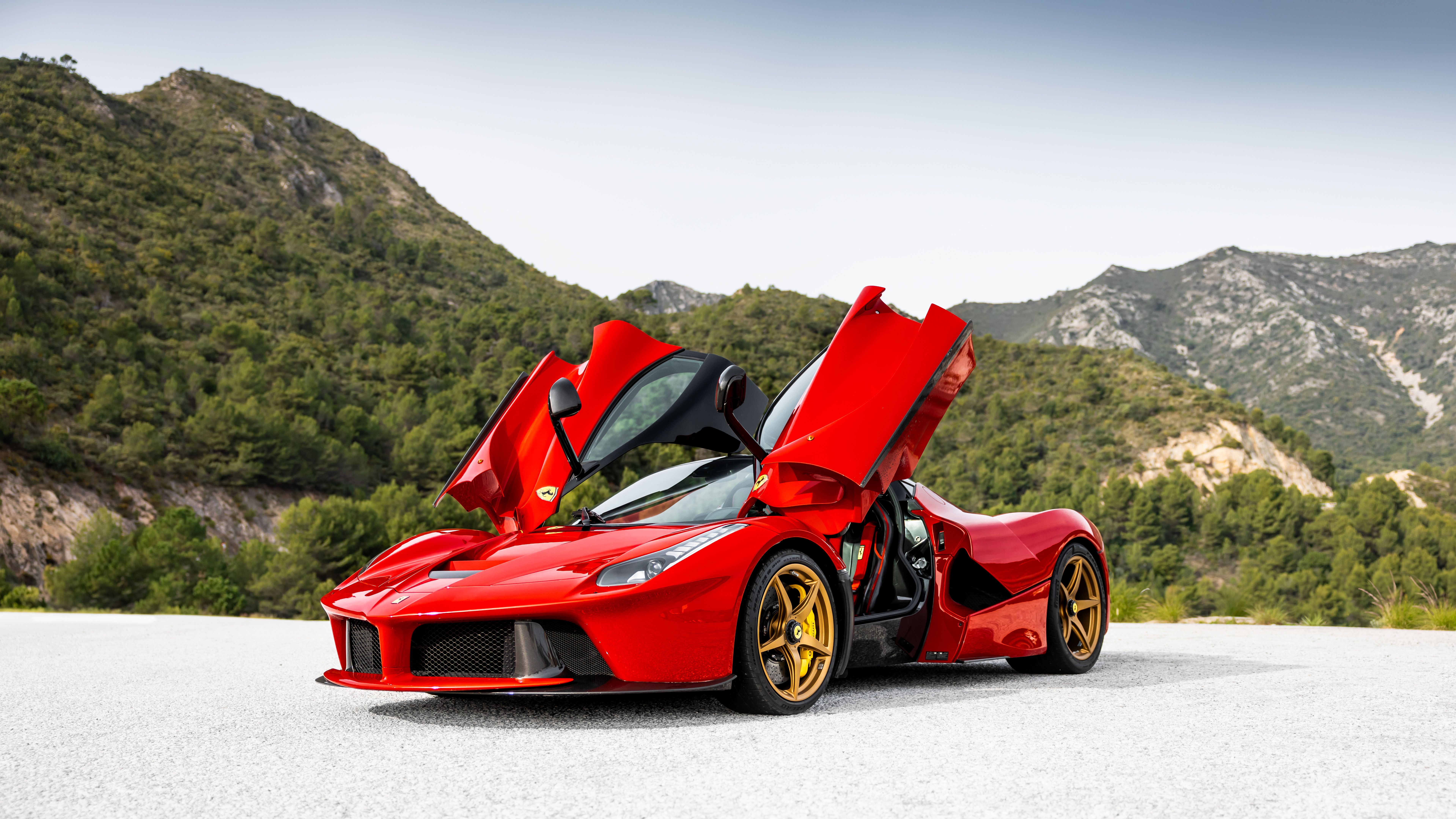 Red Ferrari LaFerrari with doors open, side front view in the mountains